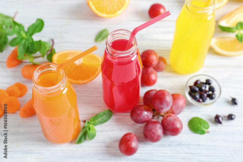 Delicious juices in bottles and fruits on wooden table Delicious juices in bottles and fruits on wooden table