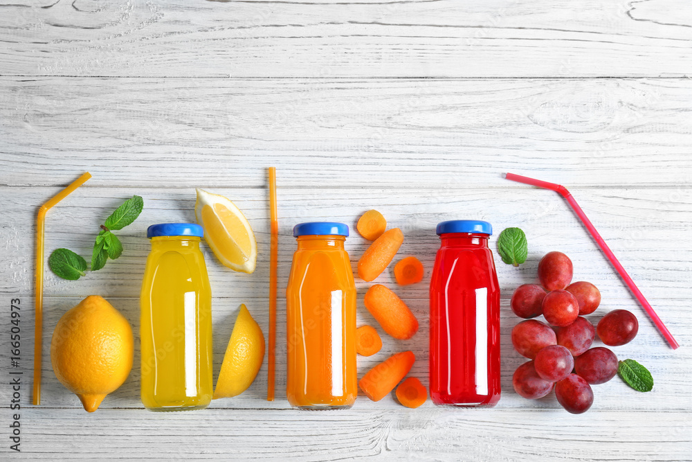 Fototapeta premium Delicious juices in bottles and fruits on wooden background