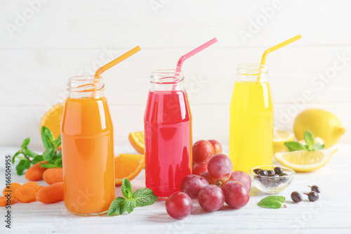 Delicious juices in bottles and fruits on wooden table © Africa Studio