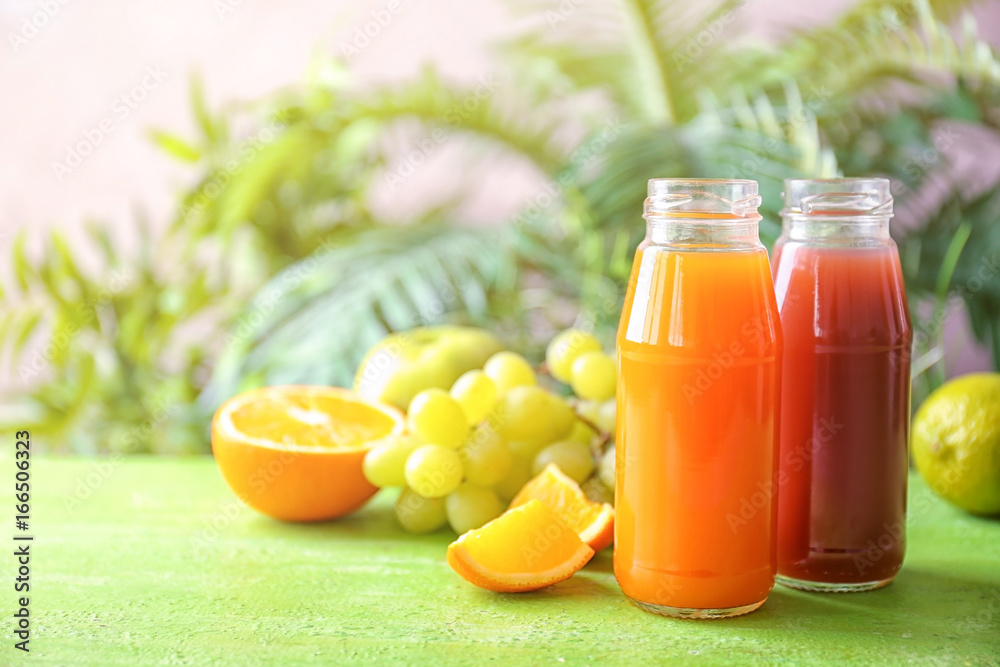 Delicious juices in bottles and fruits on table