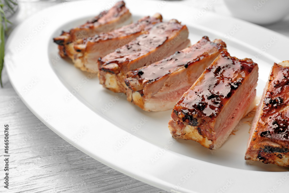 Plate with delicious pork ribs on wooden table, closeup Plate with delicious pork ribs on wooden table, closeup