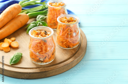 Jars with delicious carrot raisin salad on cutting board