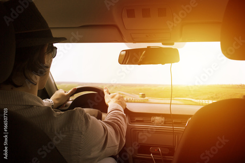 video recorder driving a car on highway. The hidden camera is hidden in the rear-view mirrorThe man in the hat drives the car. Sunset filter effect. Safety on the road. The road to success © luuuusa