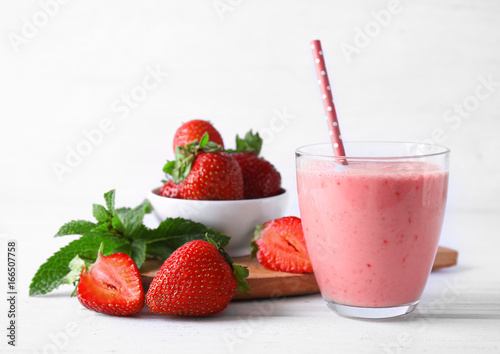Glass of delicious strawberry homemade smoothie on light background