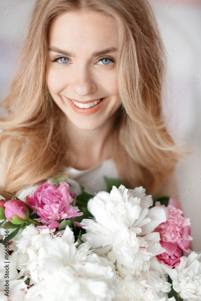 Beautiful young woman with bouquet of peonies, closeup