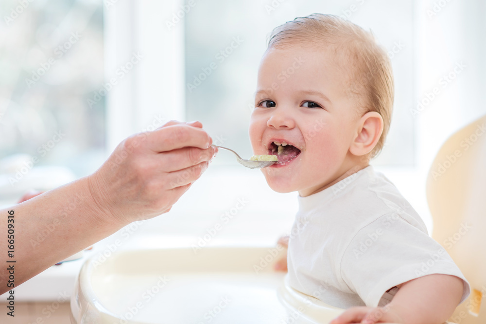 grandmother gives baby food from a spoon grandmother gives baby food from a spoon