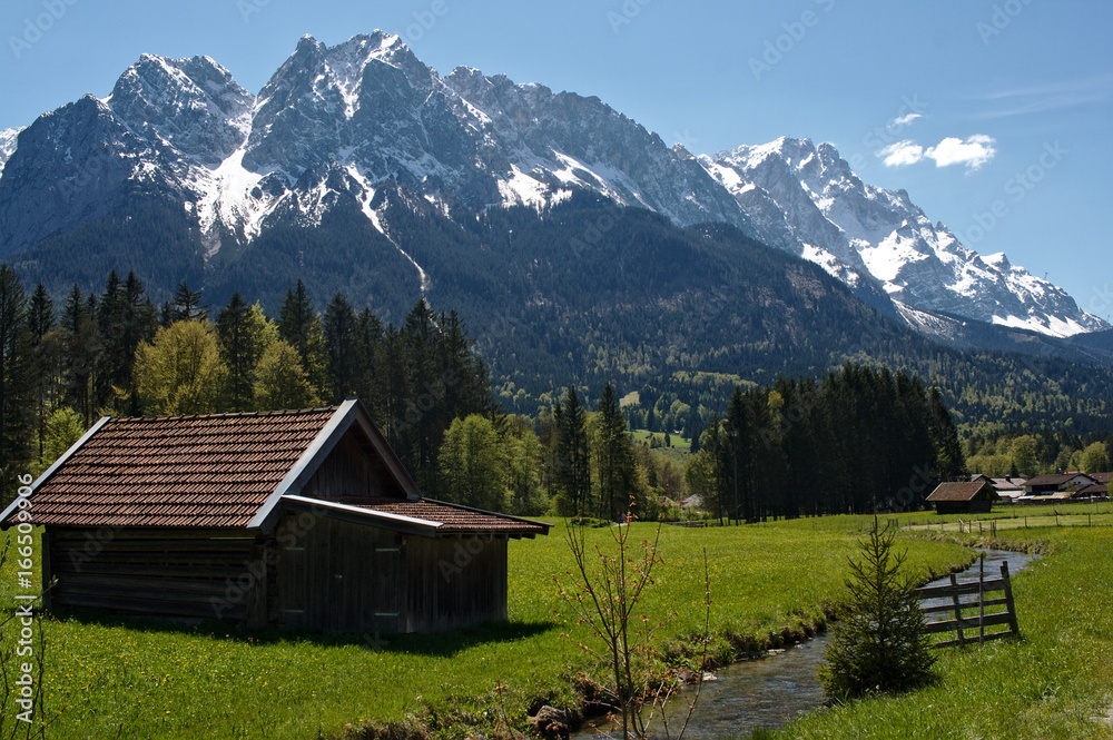 Alpine hut on a meadow with the Bavarian alps in the background, Garmisch-Partenkirchen, Bavaria, 2016 