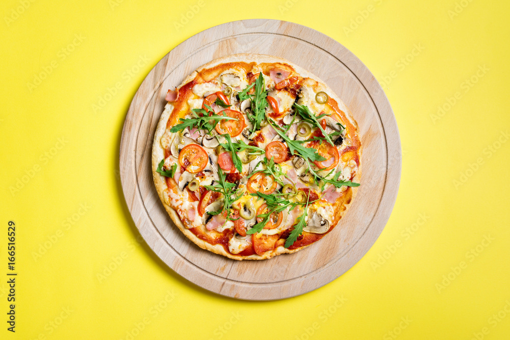 Pizza on wooden board on yellow background, top view Pizza on wooden board on yellow background, top view