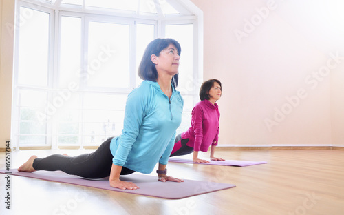 Active sportive mature women doing exercise in fitness studio