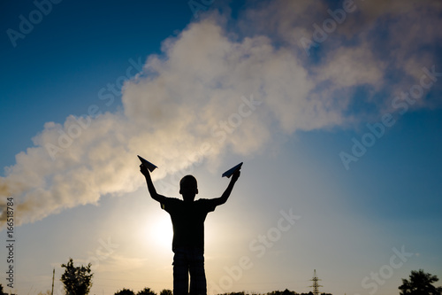 A happy child is playing with a paper airplane at sunset. Classes with children outdoors. Life style