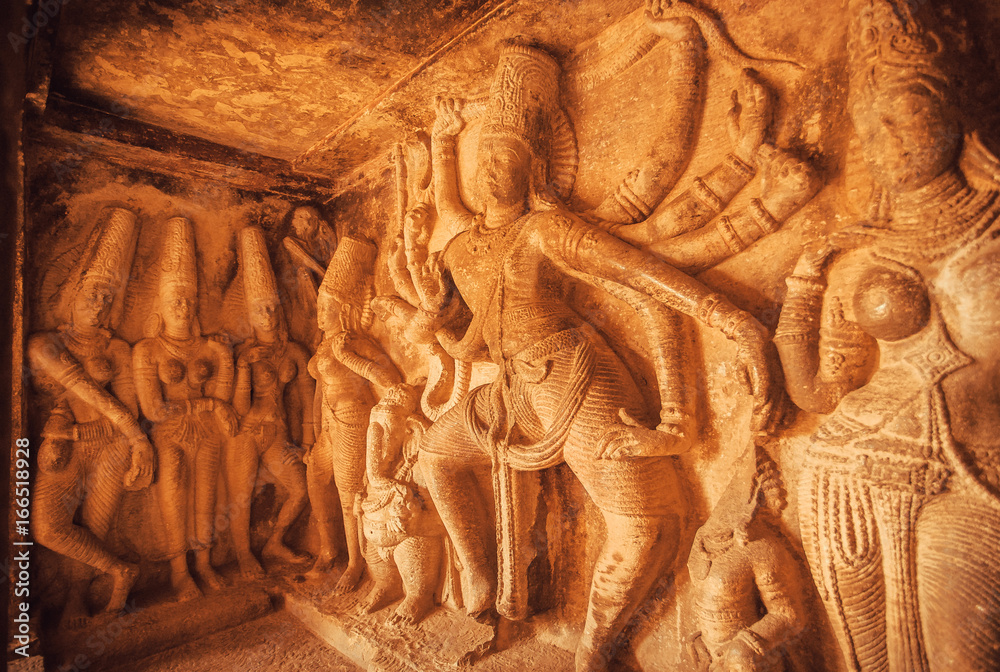 Dancing Shiva Lord sculpture with many dands on wall of old relief. Ancient Indian architecture in Aihole, India