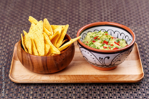 mexico - guacamole and nachos in bowl on wooden plate