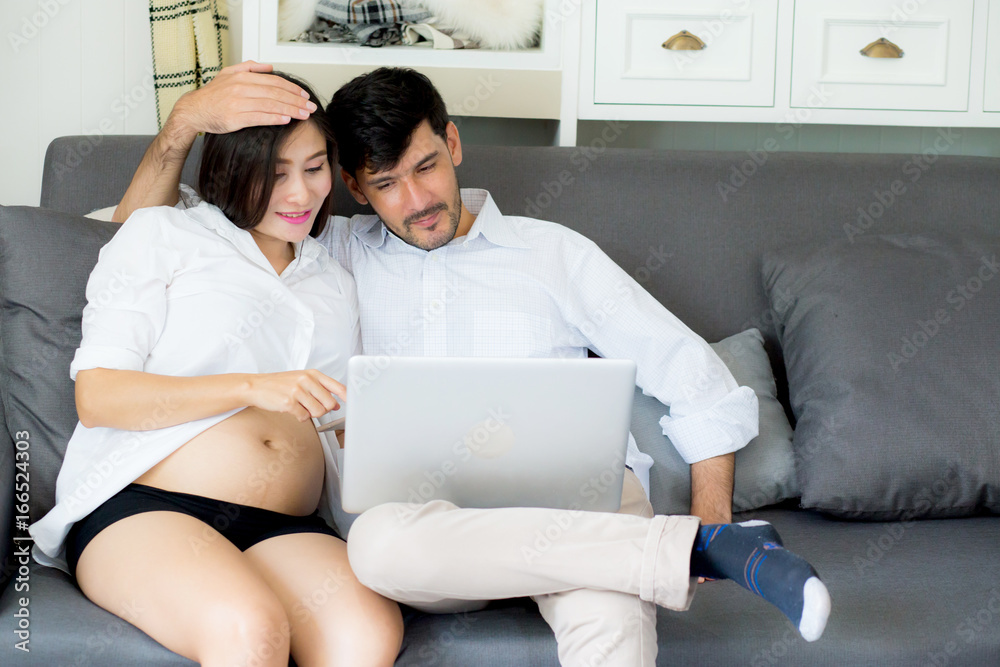 Portrait of a asian young couple husband and wife sitting on the sofa while using notebook computer in living room. Portrait of a asian young couple husband and wife sitting on the sofa while using notebook computer in living room.
