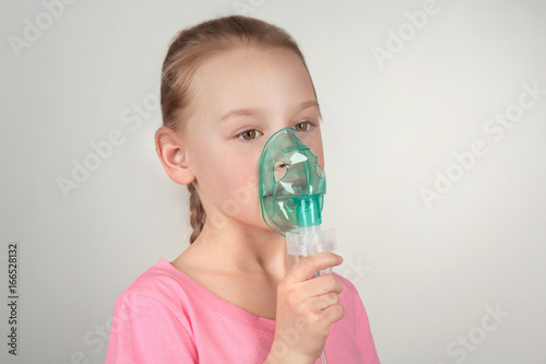 Girl using asthma machine on light background