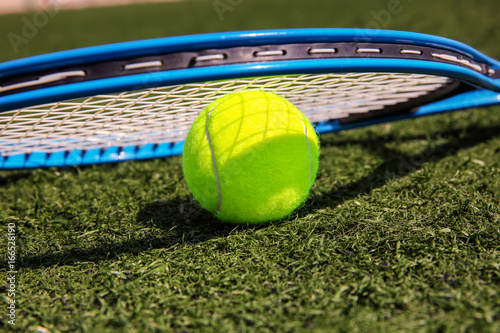 Tennis ball and racket on fresh green grass outdoors © Africa Studio