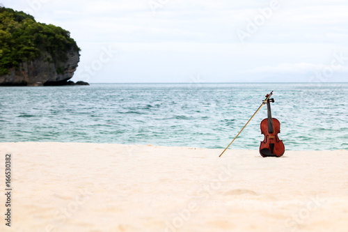 Fototapeta Naklejka Na Ścianę i Meble -  The violin on the white sandy beach by the sea