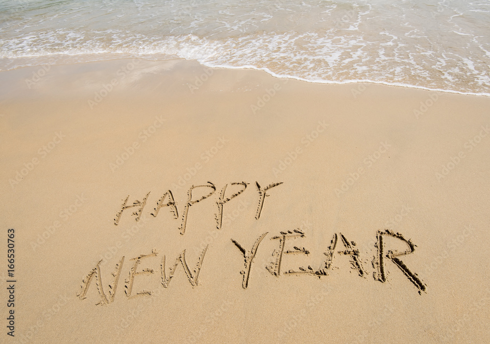 Fototapeta premium happy new year written in the sand