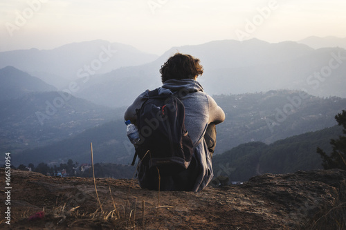 Chico joven de espaldas contemplando las montañas en soledad photo