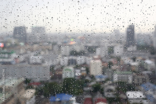 Water rain drops on window glass against blur image of building in bangkok city in thailand at the evening  Rainy day.