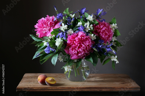 Beautiful bouquet of peonies  irises and Jasmine in the jar on the table.