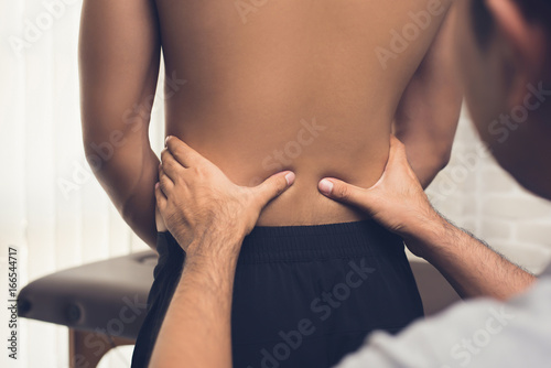 Therapist giving massage to back pain patient in clinic