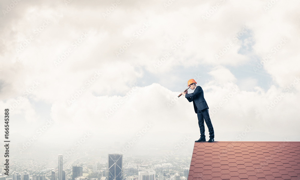 Engineer man standing on roof and looking in spyglass. Mixed med Engineer man standing on roof and looking in spyglass. Mixed med