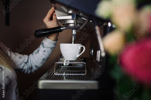 Coffee machine make espresso in cup. female barista preparing coffee in cafe