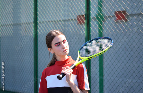 Portrait of a young girl with tennis racket on shoulder