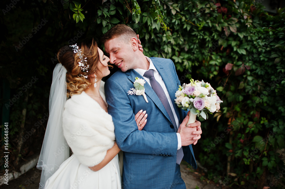 Attractive young wedding couple enjoying each other's company outdoor next to the ivy wall. Attractive young wedding couple enjoying each other's company outdoor next to the ivy wall.