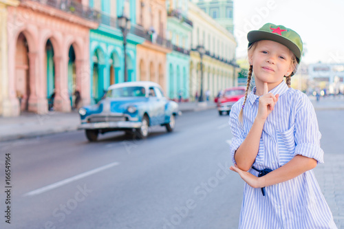 Adorable little girl in popular area in Old Havana, Cuba. Portrait of kid background vintage classic american car
