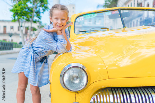 Adorable little girl in popular area in Old Havana, Cuba. Portrait of kid background vintage classic american car