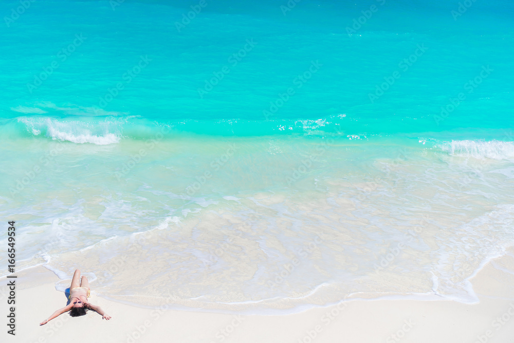 Top view of young beautiful girl lying on the beach at shallow tropical water on the seashore Top view of young beautiful girl lying on the beach at shallow tropical water on the seashore