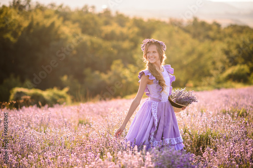 Beautiful girl in a field of lavender on sunset. Girl in amazing dress walk on the lavender field.