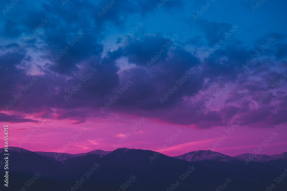 Photo depicting a beautiful moody frosty landscape. European alpine mountains with snow peaks on colorful evening sky background.
