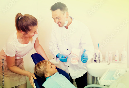 Professional in uniform is telling to young boy and mother about hygiene