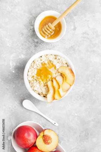 Oatmeal with nectarine and honey on a gray background. Top view. Food background. Toning