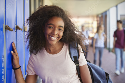 Portrait of black teenage girl by lockers in school corridor photo
