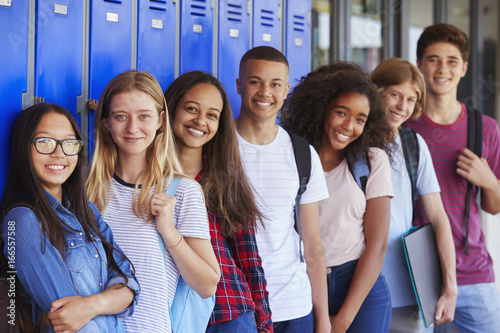 Teenage school kids smiling to camera in school corridor photo