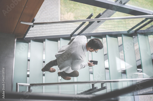 Business man walking on the stairs of business building. Business man checking e mail.