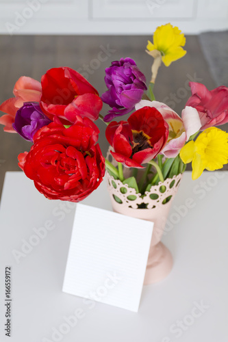 bouquet of red  tulips and narcissus with empty message card 