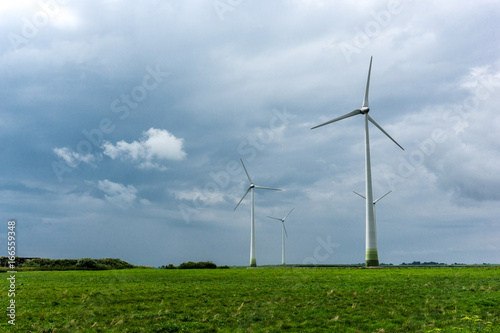 Wind Turbines and green fields on a cloudy day. Near storm