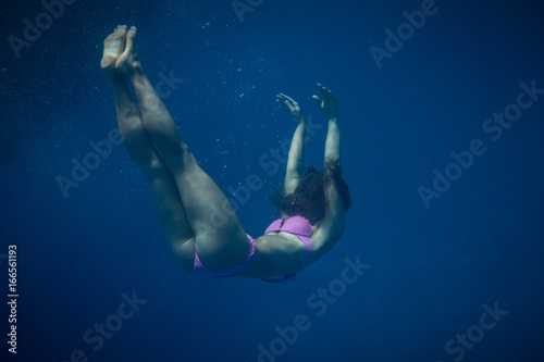 A grirl drowning in the sea water. Underwater shot in marine background