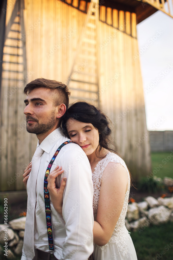 Girl in love hugging guy from behind with eyes closed