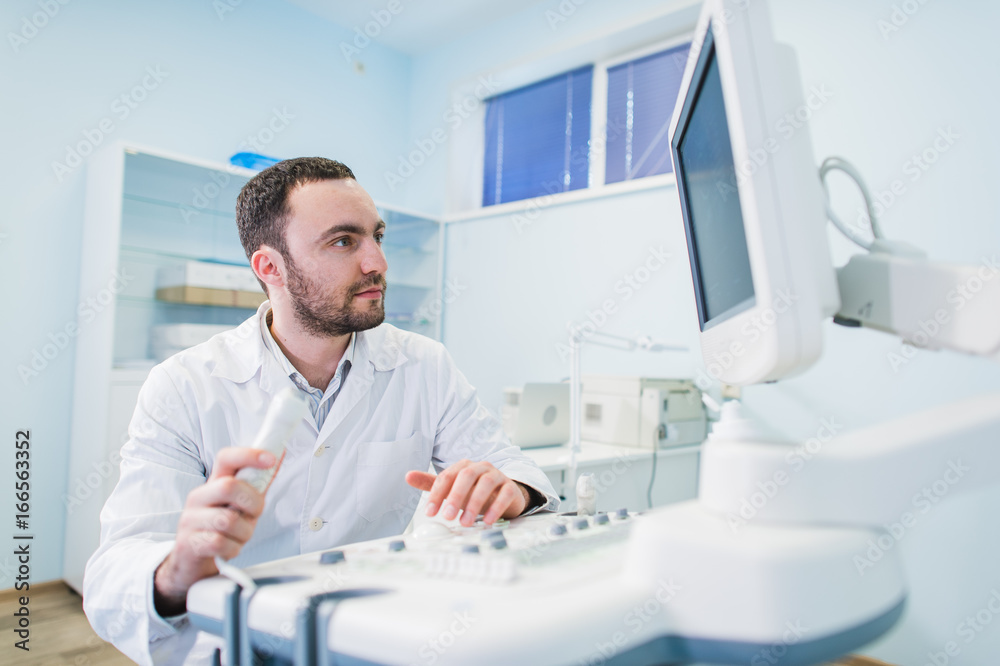 © romankosolapov - Male doctor with ultrasonic equipment during ultrasound medical examination