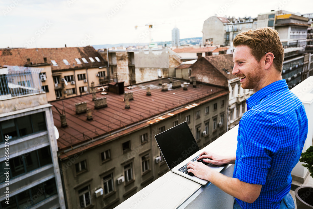 Business person using laptop on rooftop Business person using laptop on rooftop