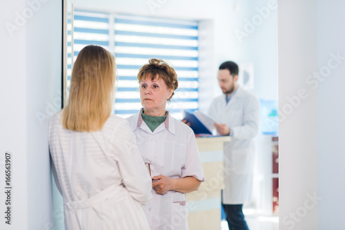 Fototapeta Naklejka Na Ścianę i Meble -  Mature doctor discussing with nurses in a hallway hospital. Doctor discussing patient case status with his medical staff after operation.