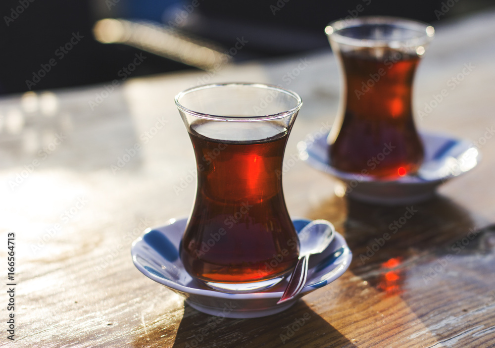 Black herbal turkish tea in traditional glass at the street cafe. Back light Black herbal turkish tea in traditional glass at the street cafe. Back light
