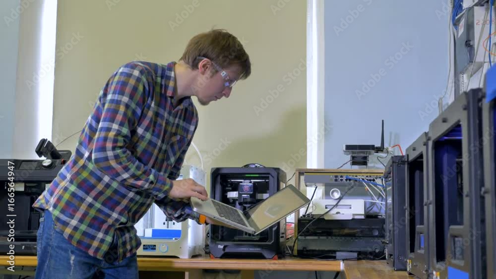 A man controls 3d-printing with his laptop. A man controls 3d-printing with his laptop.