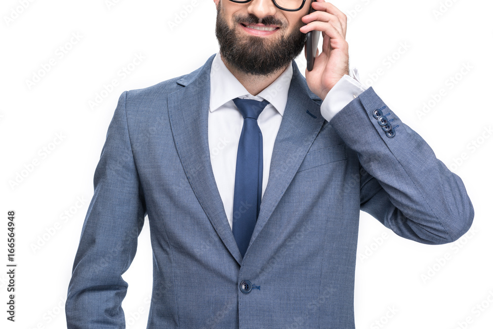 Naklejka premium cropped view of smiling businessman in grey suit using smartphone, isolated on white
