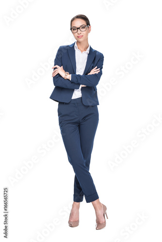 attractive smiling businesswoman with crossed arms posing in suit and eyeglasses, isolated on white
